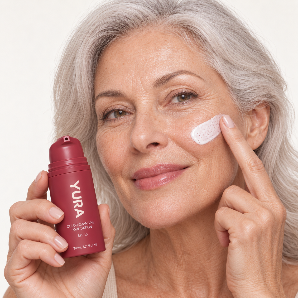 Silver-haired woman applying YURA foundation